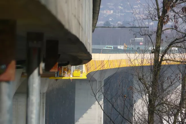 Blick auf eine Brücke, die über einer anderen Strasse verläuft, umgeben von Bäumen.