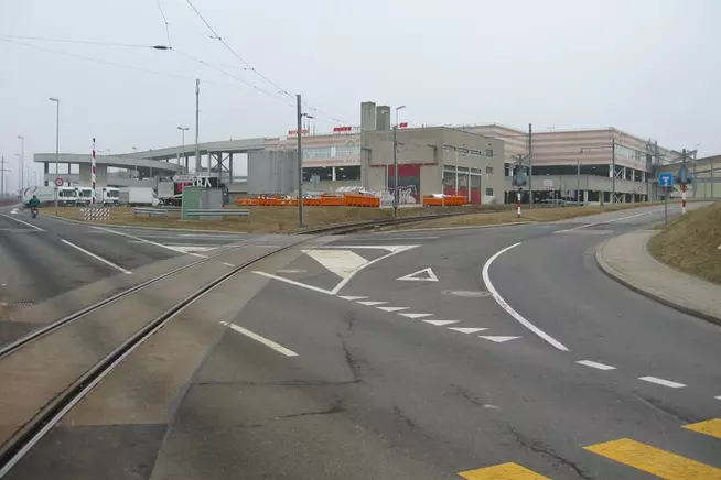 Verkehrskreuzung mit schattigem Wetter und angrenzendem Gebäude im Hintergrund.